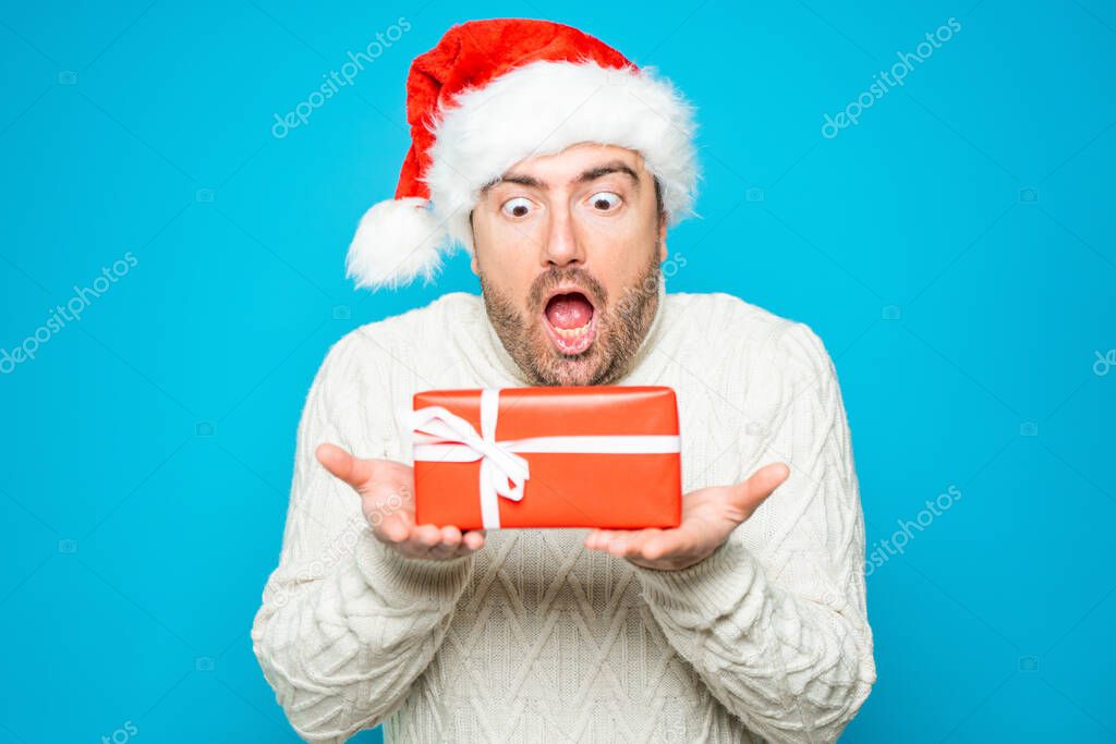 Portrait of one surprised man holding red box gift on blue background