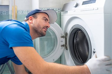 Bir tamirci arızalı mutfak fırınını tamir ediyor.