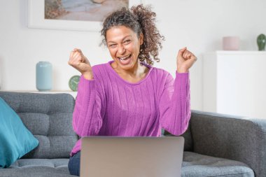 Happy black woman celebrating online win at home