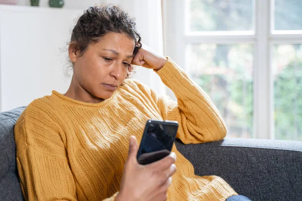 Worried black woman getting bad news on mobile phone