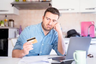Kredi kartını evde online alışveriş için kullanan bir adam.