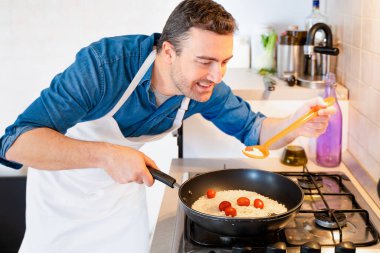 Adam evde kaşıkla yemek tarifi tadıyor.