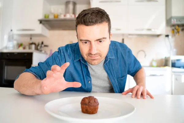 One man dieting and tempted by chocolate muffin