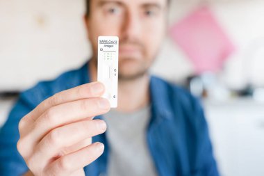 Bir adam COVID-19 için hızlı test cihazı kullanarak test sonuçlarını bekliyor