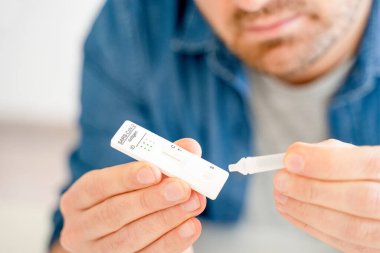 Bir adam evde antijen kiti ile Coronavirus enfeksiyonunu kontrol ediyor.