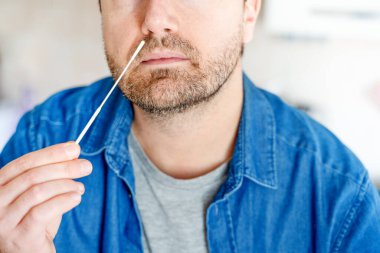 Bir adam COVID-19 için hızlı test cihazı kullanarak test sonuçlarını bekliyor