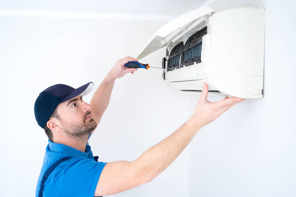 Technician installing air conditioner on the wall at home for hvac service