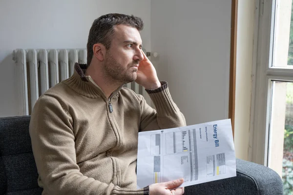 Shocked man reading some bills energy expenses on sofa living room