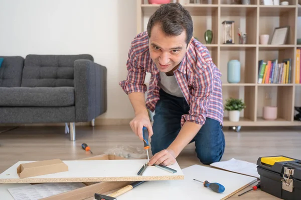 One man assembling shelf furniture and consulting Instruction