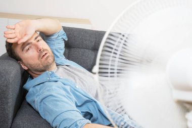 Bir adam evde yaz sıcağı yüzünden terliyor.