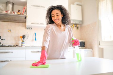 One black woman cleaning domestic kitchen at home clipart