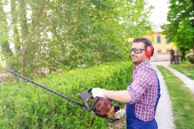 Çim biçme makinesi kullanan bir bahçıvan.