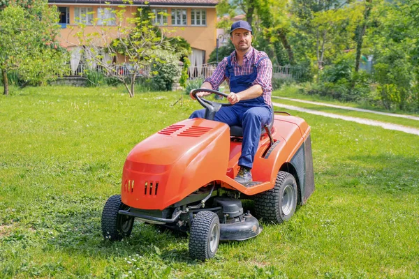 Profesyonel çim biçme makinesi işçisi ev bahçesinde çim biçiyor.