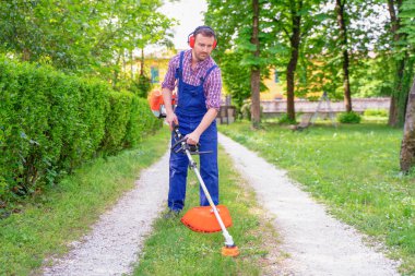 Bahçede çim biçme makası kullanan bir bahçıvan.