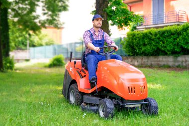 Professional lawn mower worker cutting grass in home garden