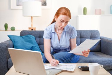 Finans bütçesini evde hesap makinesiyle analiz eden kadın