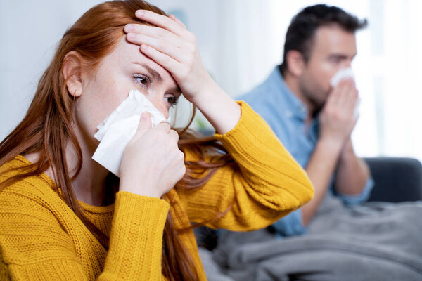 Sick couple blowing nose suffering flu symptoms together