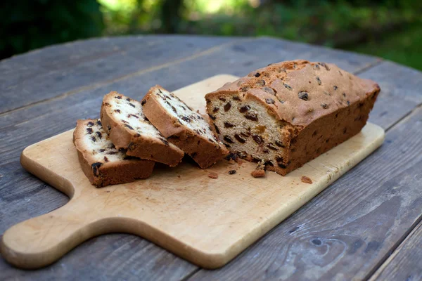 Pain au raisin tranché sur une planche à découper sur une table en bois — Photo