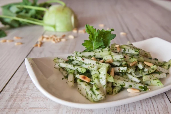 Fresh kohlrabi salad with pine nuts on wooden table — Stock Photo, Image