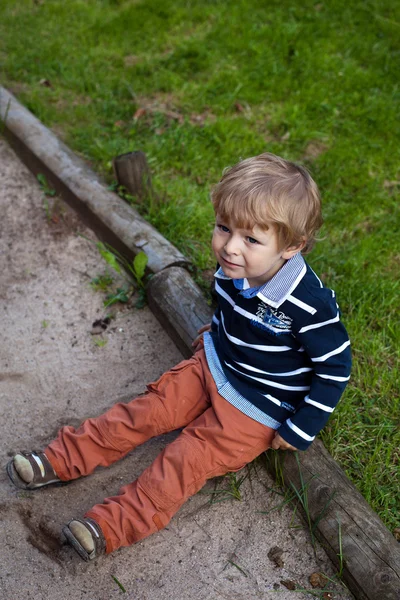 Χαριτωμένο μικρό παιδί που κάθεται στο πράσινο γρασίδι — Φωτογραφία Αρχείου