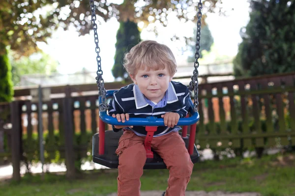 Adorable toddler on playground swing summer — Stock Photo, Image