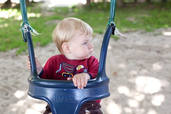 Doce menino no parque infantil swing verão — Fotografia de Stock