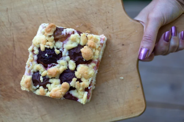 Torta di prugne fresche sul tagliere con mano donna — Foto Stock