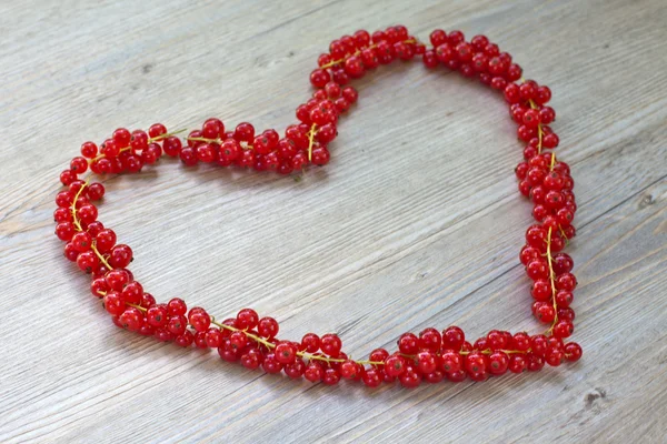 Corazón hecho con bayas de grosella roja sobre mesa de madera —  Fotos de Stock