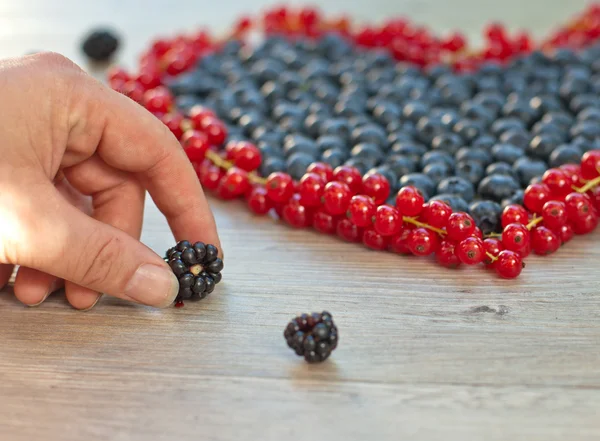 Hjärtat av bär: blåbär, röda vinbär och hand med blackberry — Stockfoto
