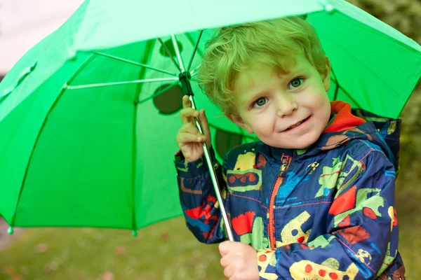 Adorable toddler under green rain umbrella autumn — Stock Photo, Image