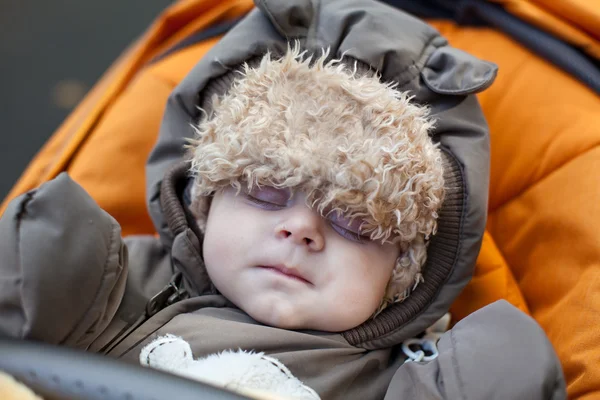 Liten pojke som sover utomhus i orange barnvagn — Stockfoto