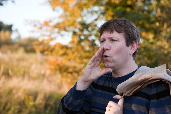 Young man shouting in autumn forest on sunny day — Stock Photo, Image