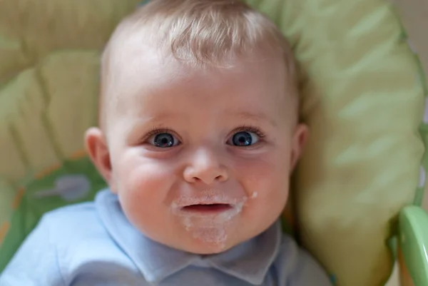 Schattige babyjongen met vuile gezicht eten melk mash — Stockfoto