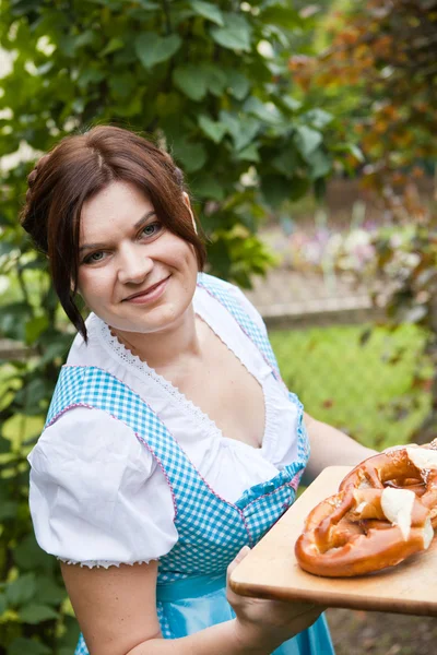 Happy beautiful woman in dirndl dress holding Oktoberfest pretz — Stok fotoğraf