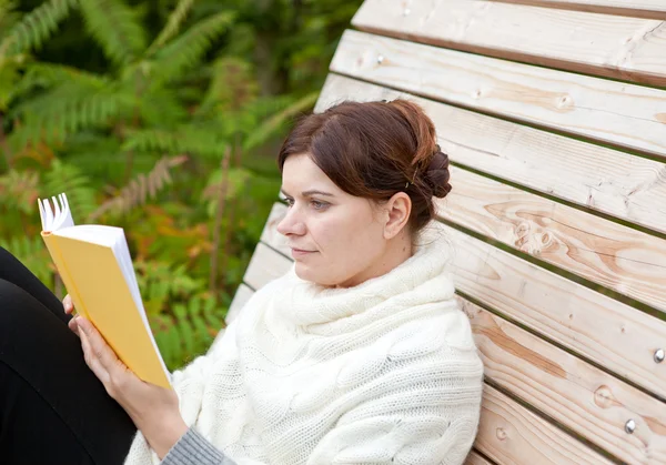 Beautiful woman reading book on bench — Stock Photo, Image