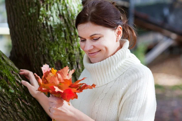 Mulher bonita no parque de outono recolhe folhas — Fotografia de Stock