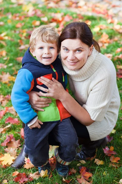 Lilla barn pojke och ung mamma i höst park — Stockfoto