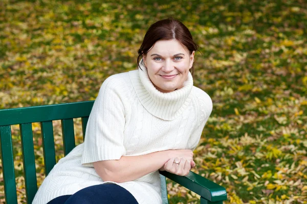 Sonbahar parkta bankta oturan güzel kadın — Stok fotoğraf