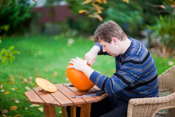 Молодой человек делает тыкву на Хэллоуин — стоковое фото