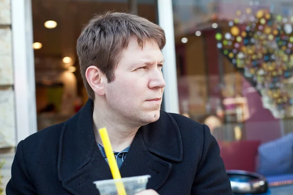 Young man drinking juice in city cafe — Stock Photo, Image