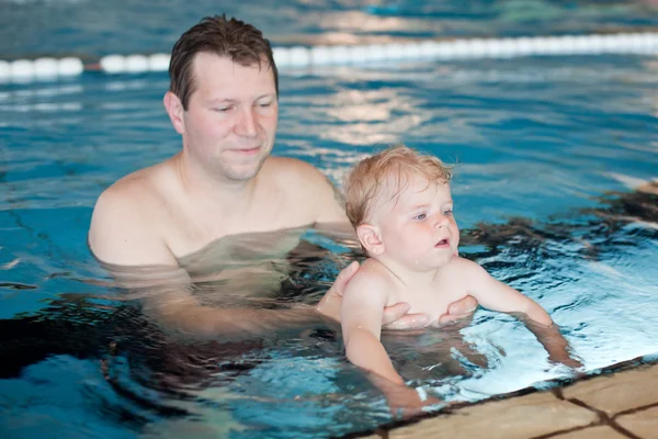 Vader en baby jongen zwemmen in een zwembad — Stockfoto