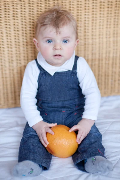 Очаровательный мальчик с большим апельсином — стоковое фото
