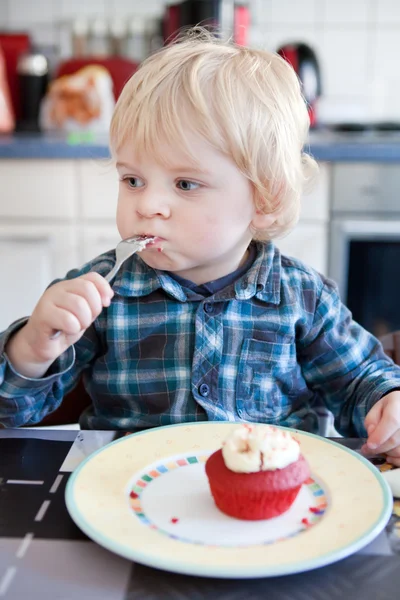 Little boy eating red cupcake — Stock Photo, Image