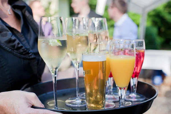 Ober met schotel van SAP, champagne, cocktails en bier glazen — Stockfoto