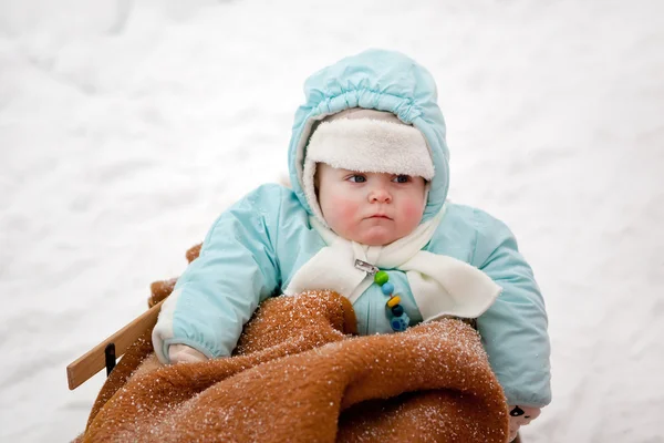 Маленький мальчик в санях в зимний снежный день — стоковое фото