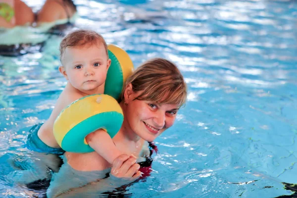 Bebé pequeno com olhos azuis aprendendo a nadar — Fotografia de Stock