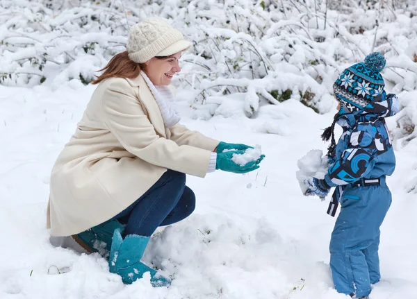 Madre y niño divirtiéndose con la nieve en el día de invierno —  Fotos de Stock