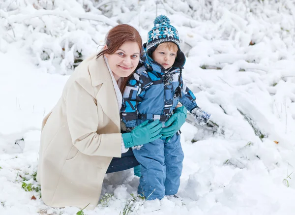 Young woman and her little son having fun with snow on winter da — Stock Photo, Image