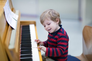 Two years old toddler boy playing piano clipart