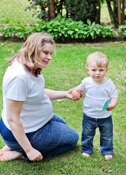 Unga gravid kvinna och Lille son i sommarträdgård — Stockfoto